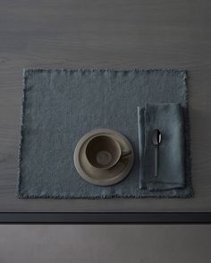 a place mat with a bowl, plate and spoon on it next to a napkin