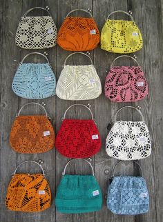 nine crocheted purses sitting on top of a wooden table