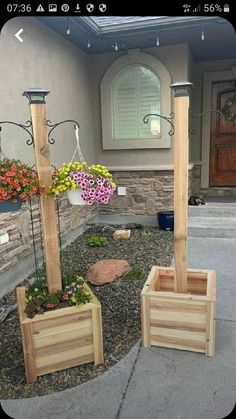 three wooden planters in front of a house with flowers growing out of the ground