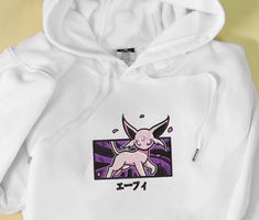 The Espeon Embroidered Hoodie is a must-have for any Pokémon fan! Made with premium quality materials, this sweatshirt features a beautifully embroidered Espeon design that adds a touch of elegance to your outfit. Its soft and cozy fabric ensures ultimate comfort, making it perfect for everyday wear or lounging at home. With its versatile style, this hoodie will easily become your go-to wardrobe staple. Whether you’re a collector or simply looking for a unique gift, this Espeon Embroidered Pokemon Hoodie, Unique Sweatshirt, Cozy Fabric, All Pokemon, Perfect Gift For Him, Embroidered Hoodie, Embroidered Sweatshirts, Couple Shirts, Graphic Crewneck