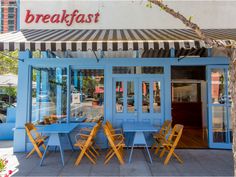 the outside of a restaurant with blue tables and chairs