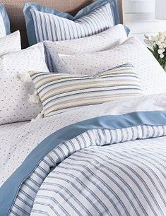 a bed with blue and white striped comforter, pillows and pillow cases on it