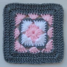 a crocheted square with a pink and white flower in the center is shown