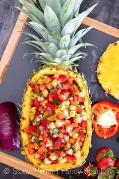 a pineapple with tomatoes, onions and other fruits