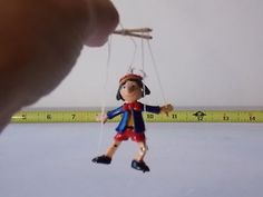 a hand holding a doll with a measuring tape behind it