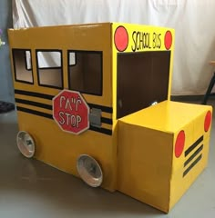 a cardboard school bus made to look like it is painted yellow and has a stop sign on the door