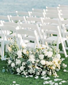 white chairs are set up on the grass for an outdoor ceremony with flowers and petals