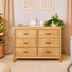 a wooden dresser with two plants on top of it in a child's room