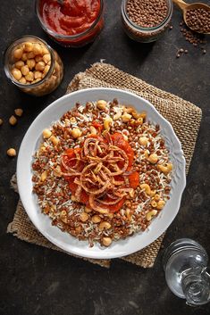 a white plate topped with lots of food on top of a table next to bowls of beans