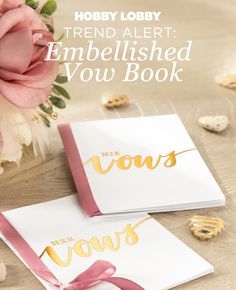 two white cards with gold foil lettering on them and pink ribbon tied around the edges