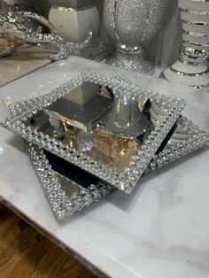 three silver dishes on top of a white marble counter with decorative objects in the background