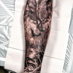 a man's arm with two wolfs on it and trees in the background