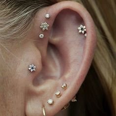 an ear with three different piercings attached to the side of it, and two smaller ones