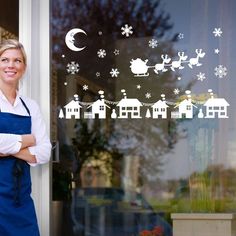 a woman standing in front of a window with santa's sleigh decals on it