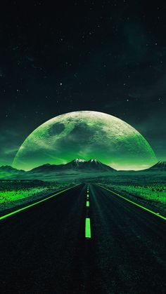 an empty road with mountains in the distance and green lights on it at night time