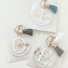 three personalized acrylic key chains with tassels are shown on top of each other