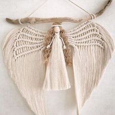 an angel wing hanging on a wall with tassels attached to the back of it