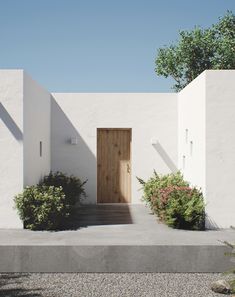 a white building with a wooden door and some bushes