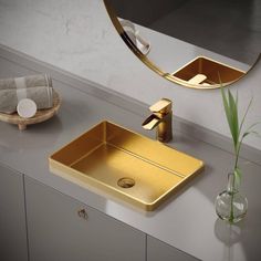 a bathroom sink sitting under a mirror next to a vase with a plant in it