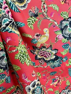 a red floral print fabric with birds and flowers on the front, as well as an orange background