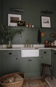 a kitchen with green painted cabinets and white counter tops, an old fashioned sink is in the center