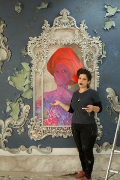 a woman standing in front of a painting