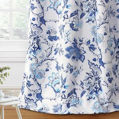 a blue and white floral curtain hanging in front of a window