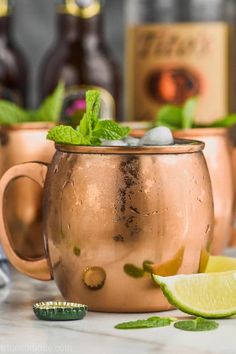 two copper mugs filled with ice and mint garnish, one has a lime slice