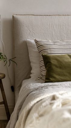 a bed with white linens and green pillows