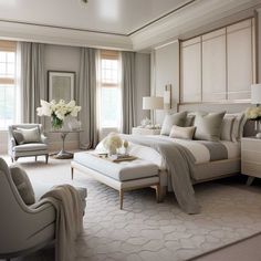 a large white bed sitting in a bedroom next to two chairs and a table with flowers on it