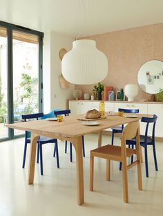 a dining room table with blue chairs and a light fixture hanging from it's ceiling