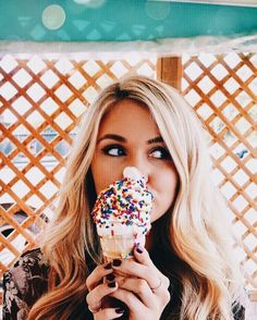 a woman eating an ice cream cone covered in sprinkles