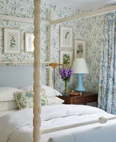 a white bed sitting in a bedroom next to a blue vase with flowers on it