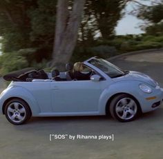 a woman driving a blue convertible car down a street