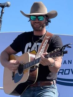 a man in a cowboy hat and sunglasses playing an acoustic guitar