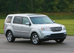 a silver honda pilot is parked in front of some grass and trees on the side of the road