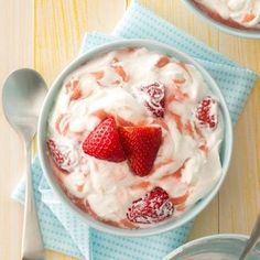 two bowls filled with yogurt and strawberries on top of blue napkins