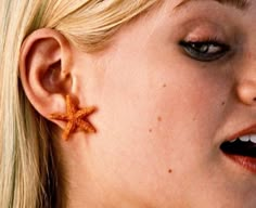 a close up of a person wearing starfish earring on their ears and nose