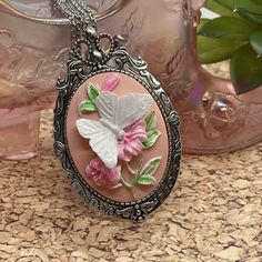 Add a touch of elegance to your outfit with this stunning 3D butterfly cameo pendant necklace. The oval-shaped pendant features a beautiful butterfly perched on a flower, with a pink main stone and nonexistent secondary stone. The pendant is made of resin and crafted with Tibetan silver, with an antique bronze and white gold finish that gives it a unique and sophisticated look.  This necklace is perfect for any occasion, especially birthdays, and makes a great gift for females who appreciate Victorian style jewelry. The necklace is 24 inches long and comes with a charm pendant/locket type, making it a great addition to any collection. The butterfly on flower theme adds a touch of whimsy and elegance to any outfit. Antique Cameo Jewelry, Pink Pendant Necklace, Faceted Glass Bead Necklace, Butterfly On Flower, Victorian Style Jewelry, Pink Pendant, Cameo Pendant Necklace, Style Birthday, 3d Rose