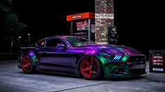 a purple and green mustang parked in front of a gas station at night with neon lights