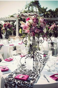 the table is set for an event with pink and white flowers in a tall vase