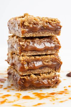 three pieces of chocolate peanut butter bars stacked on top of each other with caramel drizzle