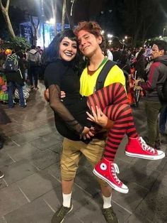 a man and woman are posing for a photo in the middle of a street at night