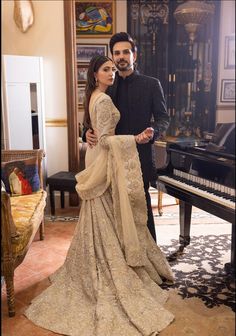 a man and woman standing next to each other in front of a piano