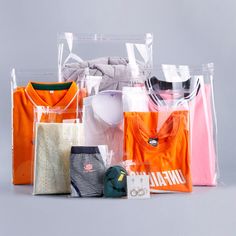 an assortment of clothing and accessories in plastic bags on a gray background with space for text