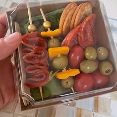 a plastic container filled with lots of different types of vegetables and meat on skewers