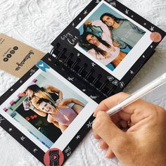 a person is holding a pen and taking pictures on a photo album with two photos