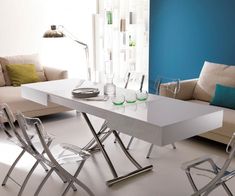 a white table with chairs around it in a living room next to a couch and coffee table