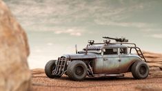 an old, rusty car is in the middle of some dirt and sand with a sky background