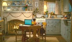 a laptop computer sitting on top of a table in front of a fire place under a chandelier